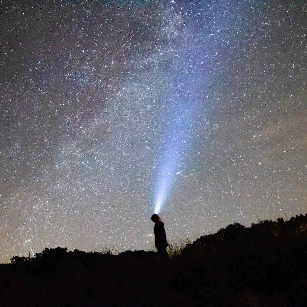 photo of a person standing under a starry sky